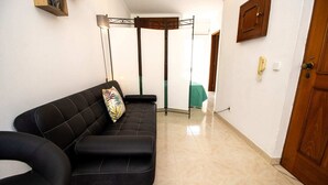 Uma sala de estar moderna com um sofá preto, um abajur e uma porta de madeira.