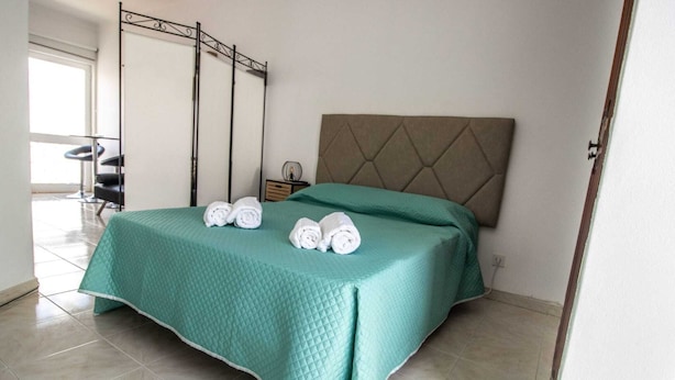 Quarto de hotel com cama, mesa de cabeceira, cadeira e janela.