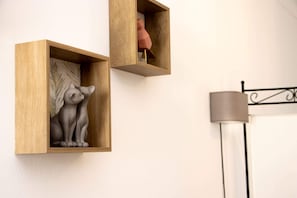 Two wooden wall-mounted shelves with sculptures, a metal bed frame, and a floor lamp.