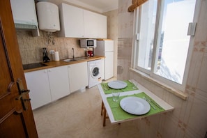 A compact kitchen with a washing machine, a microwave, and a sink.
