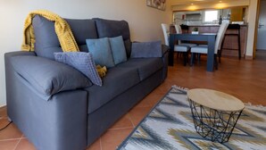 En stue med sofa, sofabord og spiseområde med stole og bord.