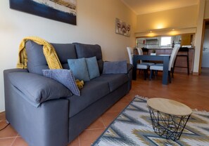 A living room with a sofa, a coffee table, and a dining area with chairs and a table.