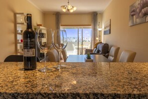 Una cucina con un piano di lavoro in granito, una bottiglia di vino e due bicchieri da vino.
