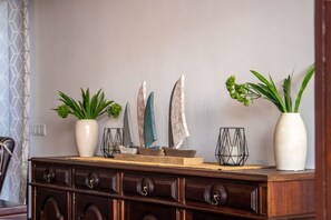 A wooden dresser with decorative items, including plants and a small sailboat model.