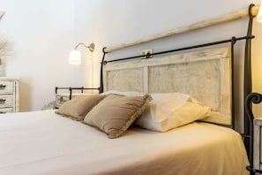 A bed with a headboard, bedside tables, and wall-mounted lamps.