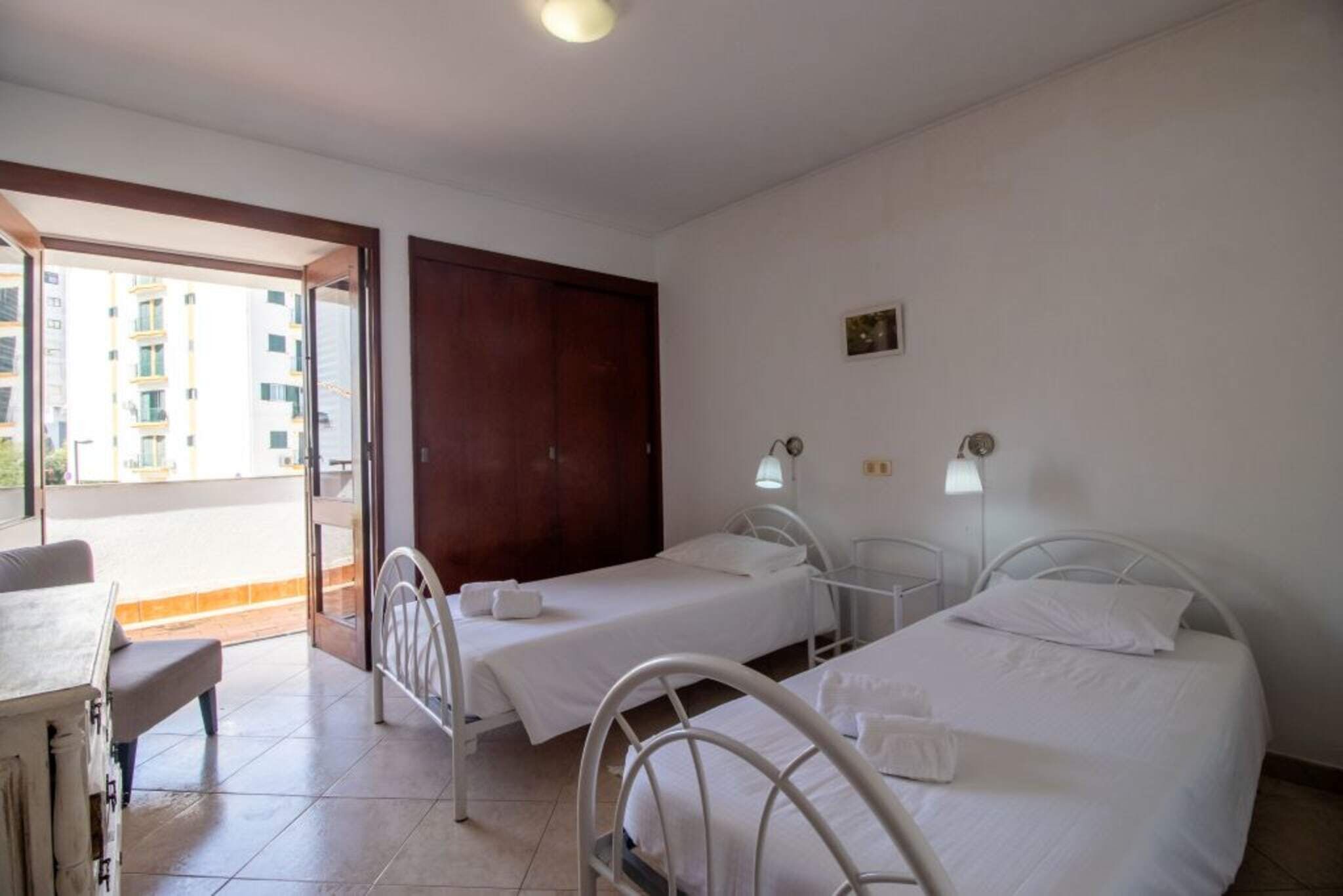 A room with two beds, a desk, and a balcony.