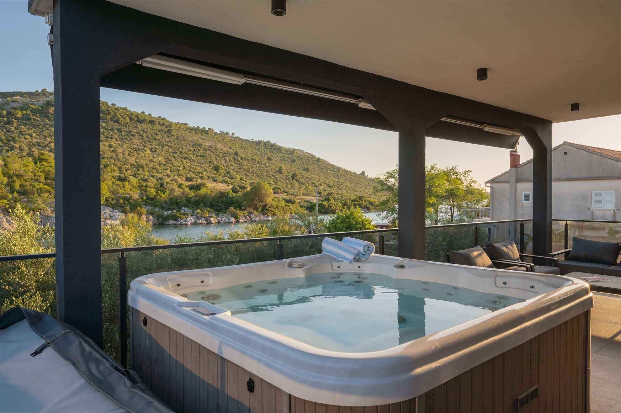 Un bain à remous sur un balcon avec vue sur une rivière et des collines.