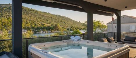 Un bain à remous sur un balcon avec vue sur une rivière et des collines.