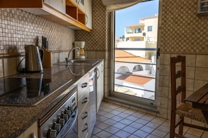 A kitchen with a window, a coffee maker, and a kettle.