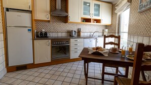 Eine Küche mit Kühlschrank, Backofen, Mikrowelle und Holzausstattung.