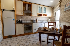 A kitchen with a refrigerator, oven, microwave, and wooden cabinets.