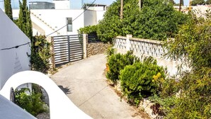 A residential area with a paved driveway, a stone wall, and a white building with a curved facade. - Casa do Mar by Urban Beach Rentals (Vale Centianes - Carvoeiro -Lagoa)