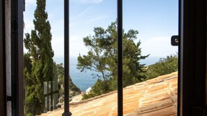 A window with a view of a coastal landscape, including trees and a body of water. - Casa do Mar by Urban Beach Rentals (Vale Centianes - Carvoeiro -Lagoa)