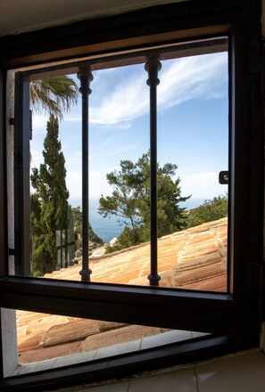 A window with a view of a coastal landscape, including trees and a body of water. - Casa do Mar by Urban Beach Rentals (Vale Centianes - Carvoeiro -Lagoa)