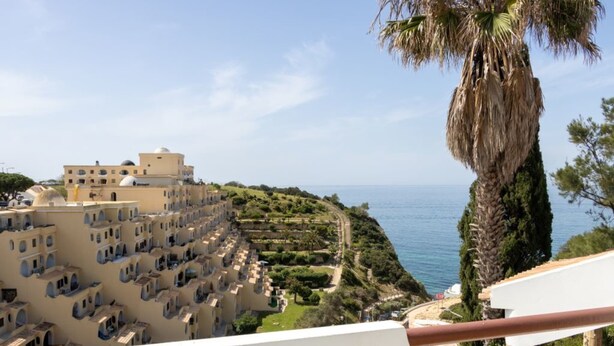 A coastal hotel with multiple buildings, a palm tree, and a view of the sea. - Casa do Mar by Urban Beach Rentals (Vale Centianes - Carvoeiro -Lagoa)