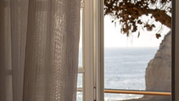 Una ventana con vista al océano y un acantilado.