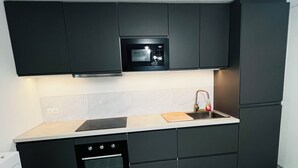A modern kitchen with dark cabinetry, a built-in microwave, a stainless steel sink, and a double oven.