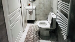 A modern bathroom with a toilet, sink, mirror, and towel rack.