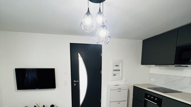A modern kitchen with a built-in oven, a microwave, and a black countertop.