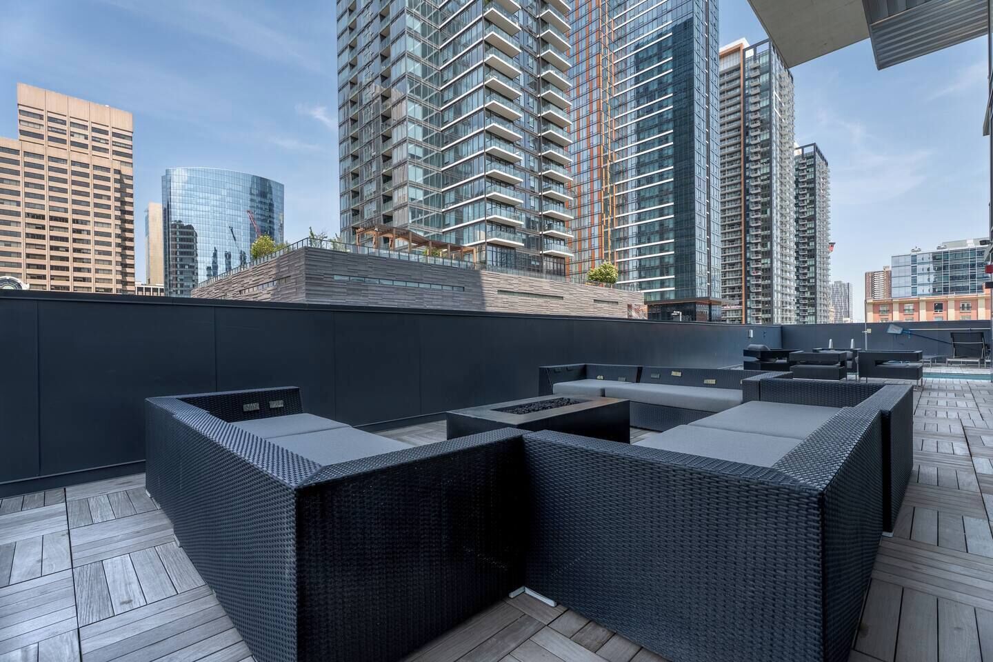 Een terras op het dak met modern buitenmeubilair en uitzicht op de skyline van de stad.