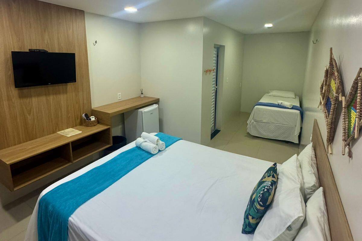 Habitación de hotel con cama, escritorio, televisión, armario y baño.