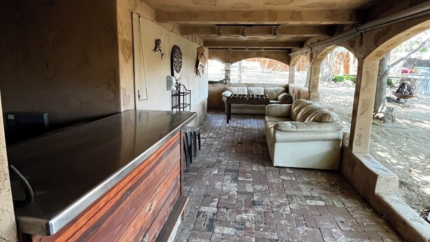 Un interior rústico con suelo de ladrillo, barra de madera, sofá y mesa de comedor.