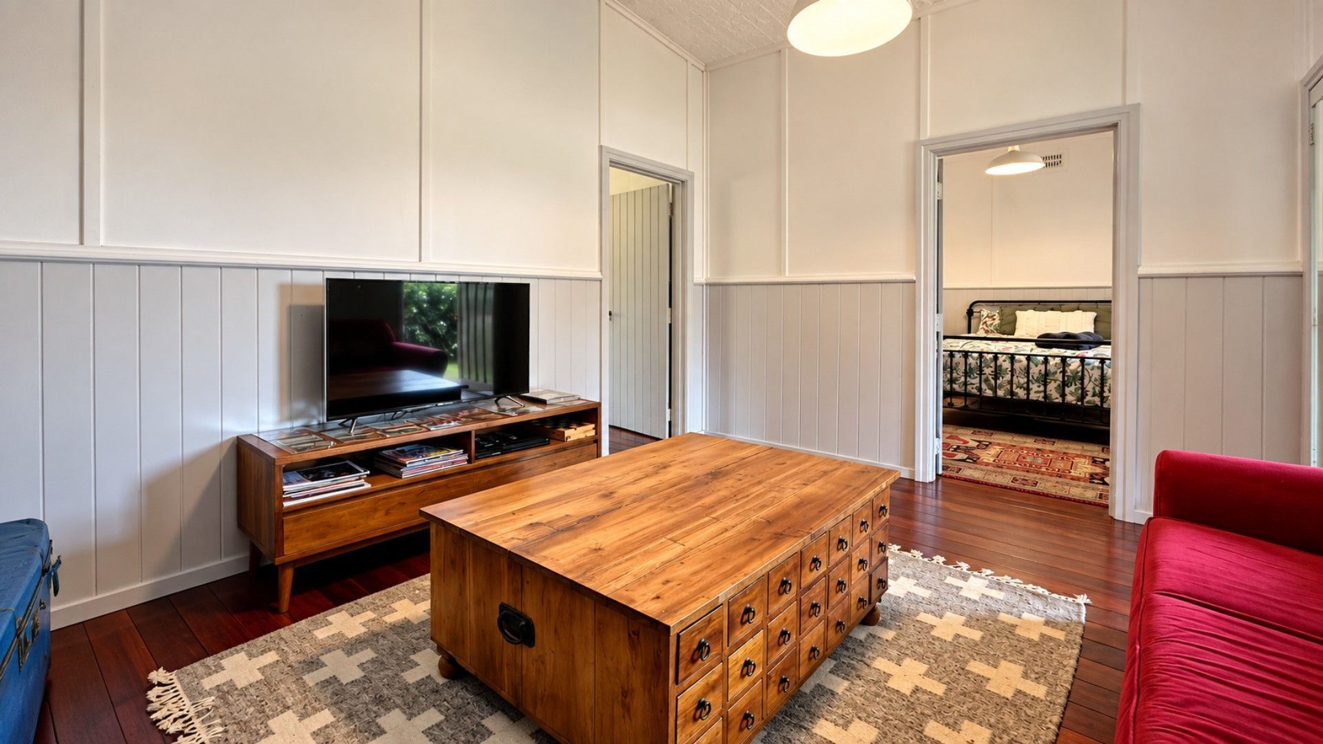 A living room with a wooden coffee table, a TV on a stand, and a red sofa.