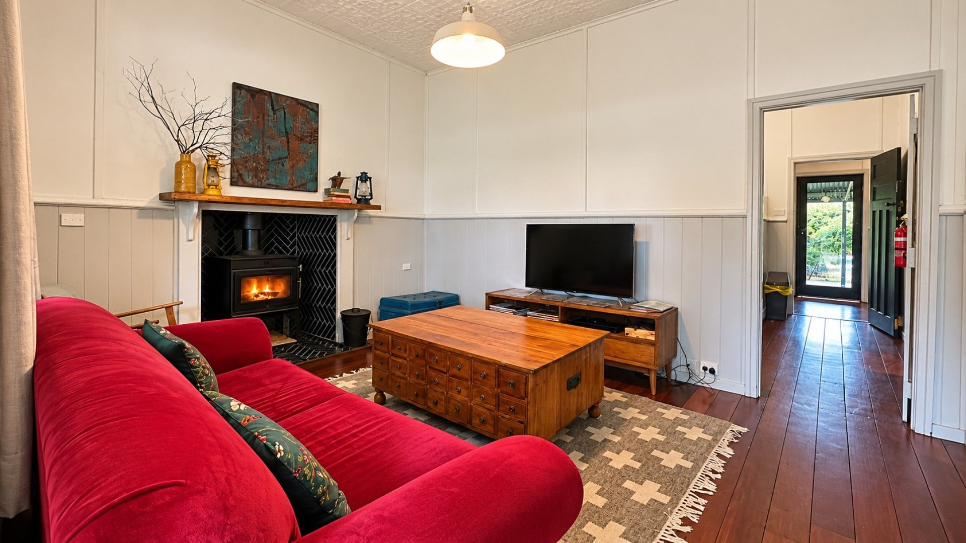 A living room with a red sofa, a wooden coffee table, a fireplace, and a television.