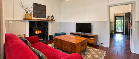 A living room with a red sofa, a wooden coffee table, a fireplace, and a television.