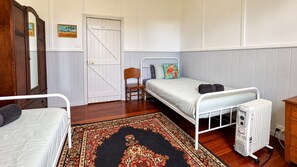 Een slaapkamer met een enkel bed, een stoel, een radiator en een deur.