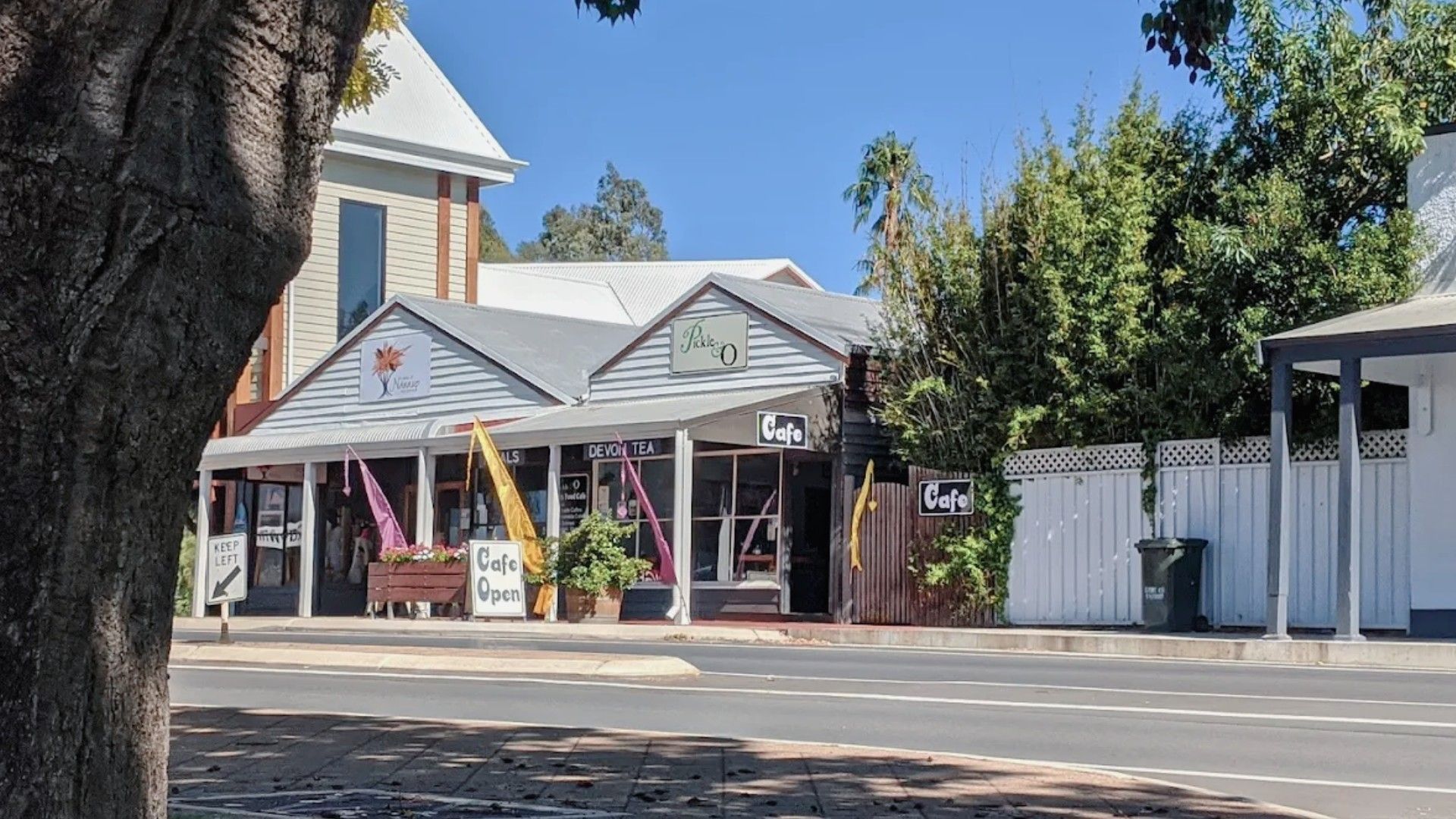 A street view with a cafe named 'Pickle O' and a sign indicating it's open.
