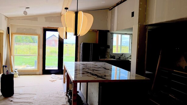 A kitchen with a marble countertop, pendant lights, and a view of a barn through the door. - Soothing 2-bedroom country Barndominium  in Beasley (Beasley)