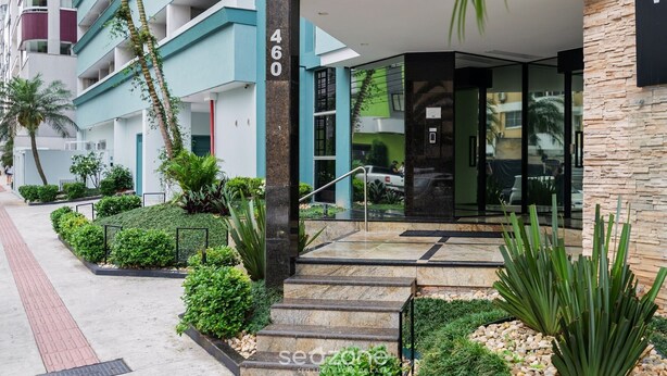 A modern building with a glass entrance, numbered 460, surrounded by well-maintained greenery and a paved walkway.