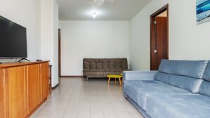 A living room with a television, a sofa, a small table, and a door.