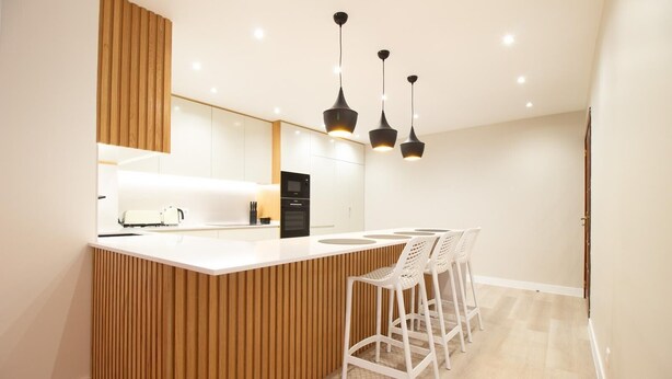 A modern kitchen with a wooden island, white bar stools, and pendant lighting. - FUNCHAL TERRACE HOUSE 3BR (Funchal)