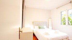 A bedroom with a bed, a bedside table, a mirror, and a window with plants outside. - FUNCHAL TERRACE HOUSE 3BR (Funchal)