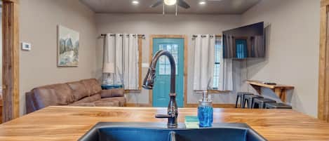 A modern kitchen with a central island, a ceiling fan, and a dining area with a TV.