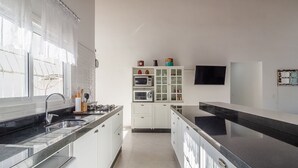 Μια σύγχρονη κουζίνα με λευκά ντουλάπια, έναν μαύρο πάγκο και έναν εντοιχισμένο φούρνο μικροκυμάτων.