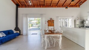 A spacious living area with a wooden ceiling, a dining table set for four, a blue sofa, and a kitchen area with a refrigerator and stove. - 5BR House w/ Gourmet Area 400m From Beach Rfi0316 (Picarras)