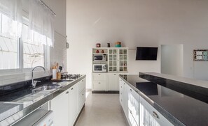 Een moderne keuken met witte kastjes, een zwart aanrechtblad en een ingebouwde magnetron.