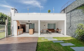 A modern house with a wooden deck, a grassy lawn, and a stone wall. - 5BR House w/ Gourmet Area 400m From Beach Rfi0316 (Picarras)