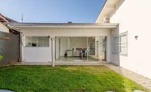 Een modern huis met een glazen deuropening, een klein terras en een verzorgd gazon.