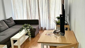 A modern living room with a grey sofa, a white coffee table, a wooden dining table, and a TV on a stand. - Smiling Holiday Home (Playa del Inglés)