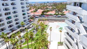 Un hotel con varias plantas, piscina y palmeras.