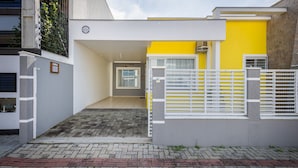 Uma casa moderna com fachada amarela e branca, portão fechado e entrada com calçada.