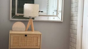 A bathroom vanity with a mirror, a lamp, and a small shelf.
