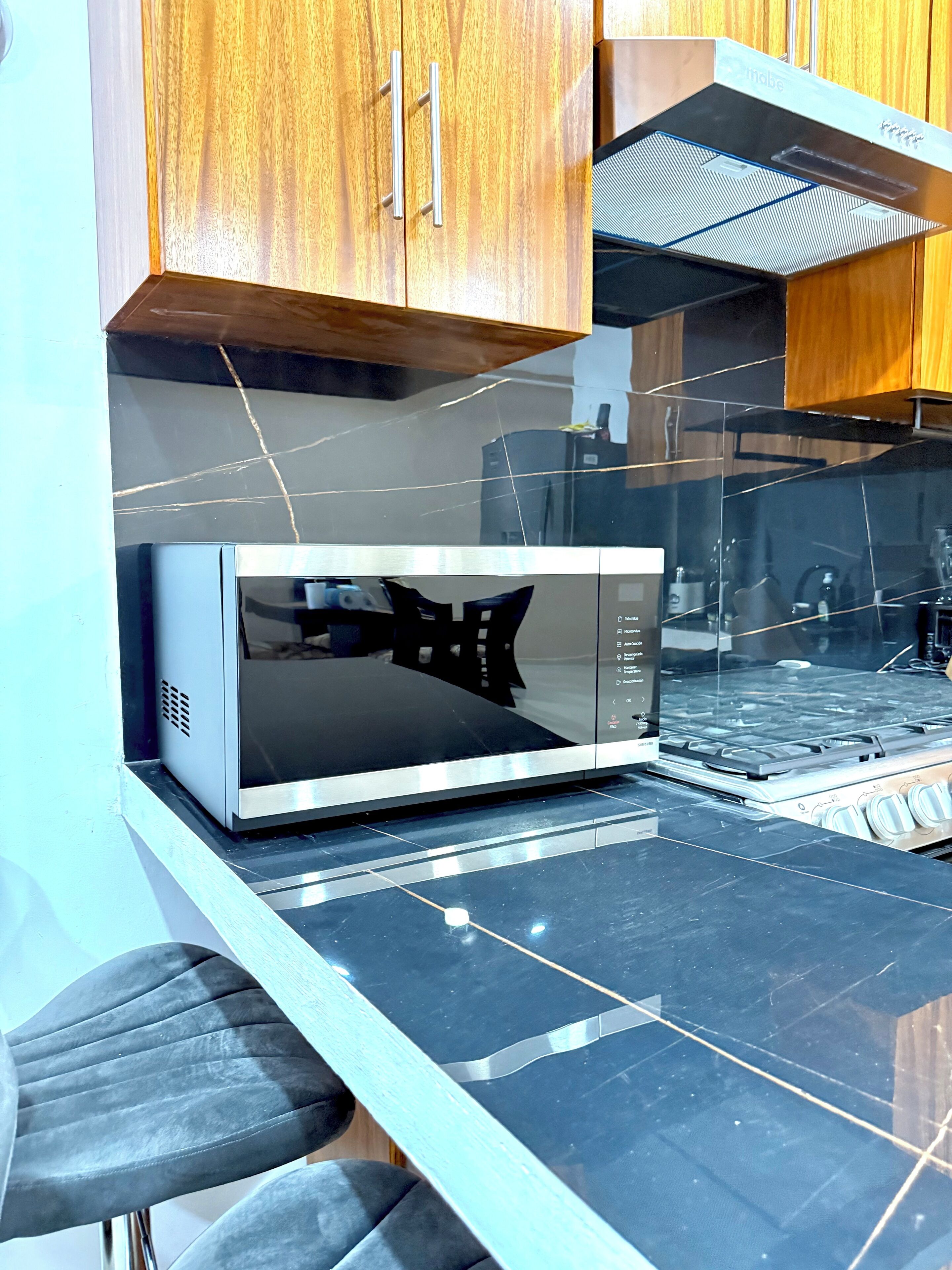 Una cucina con forno a microonde, fornello e mobili in legno.