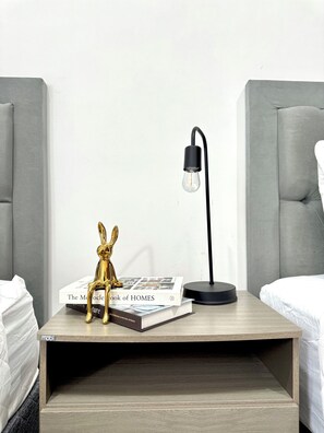 A neatly arranged bedside table with a lamp, a decorative rabbit figurine, and a book titled "The Modern Book of HOMES". - Encanto de Playa Sur  (Mazatlán)