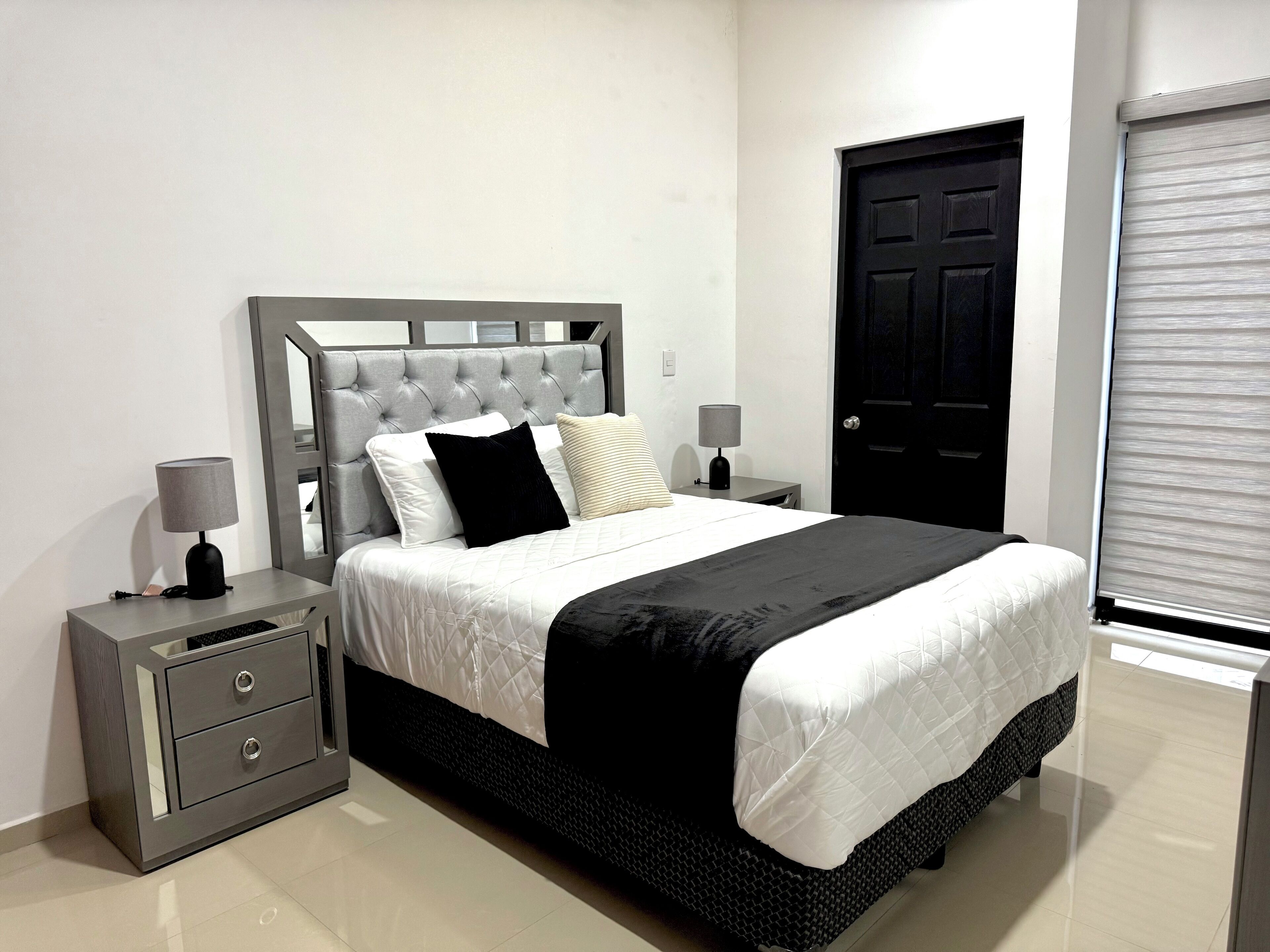 Un dormitorio ordenado con cama, mesitas de noche y una puerta.
