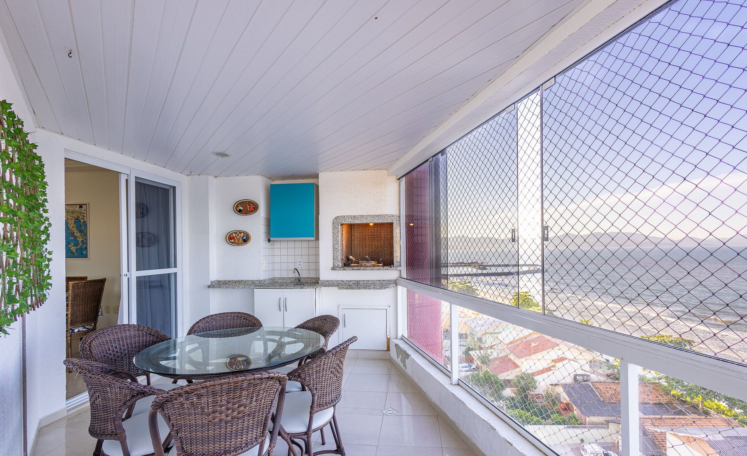 A balcony with wicker furniture, a glass table, and a view of the cityscape.
